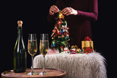 Two champagne glasses and sparkle, Christmas holiday background with decorated christmas tree, santa claus and gift boxes on black background and christmas lights. New Year Frame for your text.の写真素材