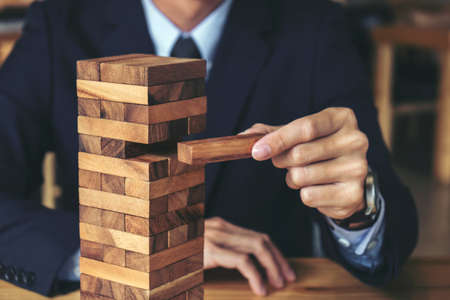 Alternative risk concept, plan and strategy in business, Risk To Make Buiness Growth Concept With Wooden Blocks, Images of hand of businesspeople placing and pulling wood block on the tower.の写真素材