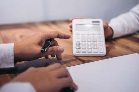 Man sign a home insurance policy on home loans, Agent agent holds loan investment chart graph documents and calculating table installment payment, Real Estate concept.の写真素材