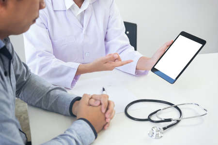 Professor Doctor presenting report and recommend a method with patient treatment on digital tablet while sitting at table.の写真素材