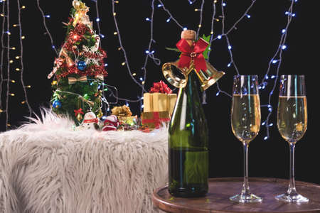 Two champagne glasses and sparkle, Christmas holiday background with decorated christmas tree, santa claus and gift boxes on black background and christmas lights. New Year Frame for your text.の写真素材