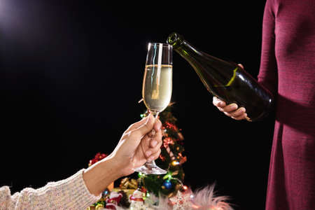 Beautiful two women holding glasses with champagne celebrating Christmas and gift boxes at corporate...