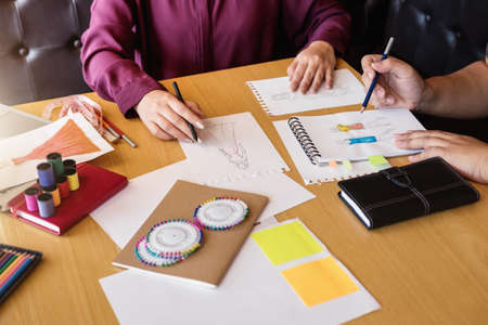 Two young professional Fashion designer colleagues working and project of drawing sketches for clothes in workplace with laptop, digital tablet and color charts, Fashion Designer Stylish Concept.の写真素材