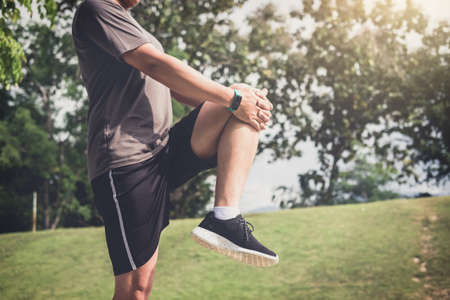 Athlete man doing some stretching exercises legs before running on outdoor.