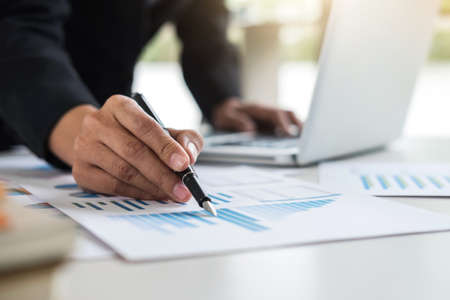 Female accountant calculations and analyzing financial graph data with calculator and laptop...