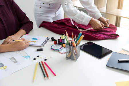 Two professional stylish fashion designer working as fashion designers measure as sketches in workshop of new collection in art, Creative Design and Artistic Concept.の写真素材