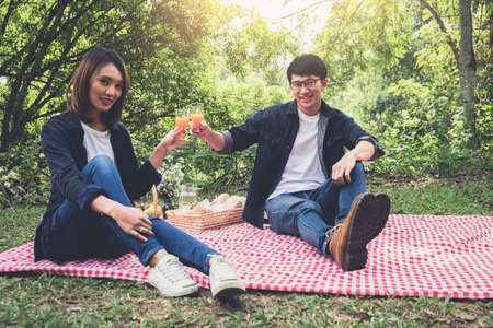 Couple in love drink a orange juice on summer picnic, leisure, holidays, eating, people and relaxation concept.の写真素材