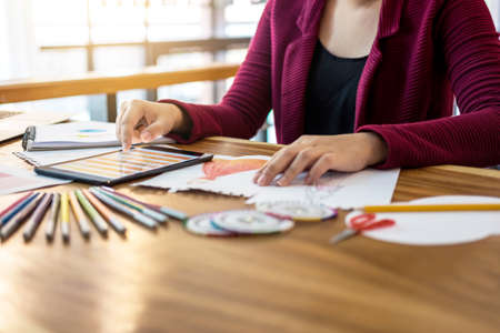 Close up of woman fashion designer at work drawing sketches for clothes in atelier with tailor tool and color charts, profession and job occupation, Fashion Designer Stylish Concept.の写真素材