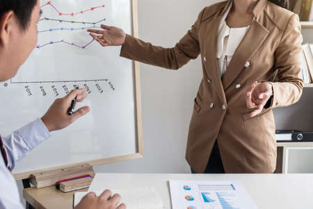Business woman leader making presentation with her colleagues, pointing to the graph on board and business strategy during meeting in modern office.の写真素材