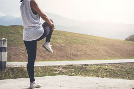 Athlete woman doing some stretching exercises legs before running on outdoor.の写真素材