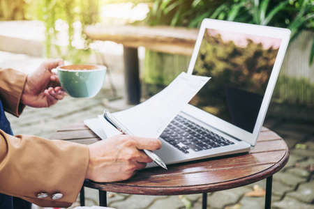Work and relax, Woman freelancer is working new project of business stragegy plan and using computer laptop, while sitting garden scenery outdoor background.の写真素材