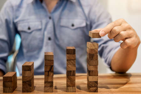 Alternative risk concept, plan and strategy in business, Risk To Make Business Growth Concept With Wooden Blocks, hand of man has piling up and stacking a wooden block.の写真素材