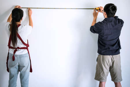 Interior working, Two painter with measure tape checking wall length in room, shape and structure.の写真素材