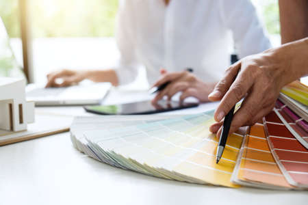 Two young women interior design or graphic designer working on project of architecture drawing with...