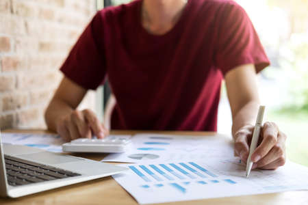 Young male working analysis finance with calculate about cost on investment, planning data on document, business strategy and accounting concept.の写真素材