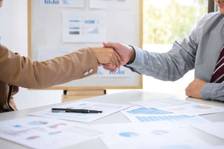 Two business people shaking hands during a meeting to sign agreement and become a business partner in the office, success, dealing, greeting & business partner concept, contract between their firms.の写真素材