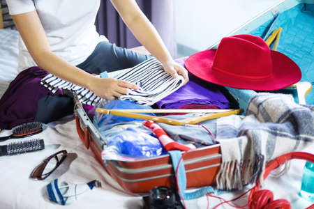 Travel and vacation concept, happiness young woman packing a lot of her clothes and stuff into...