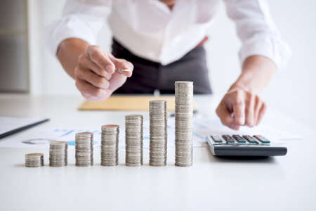 Business accountant or banker, businessman calculate and analysis with stock financial indices and putting growth stacking coin and financial costs wisely and carefully, investment and saving concept.の写真素材