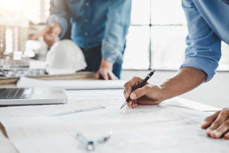 Hands of architect or engineer working on blueprint meeting for project working with partner on...