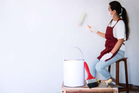 Interior working, Painter hand in white glove painting wall with paint roller in room, shape and structure.の写真素材