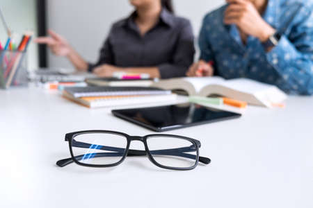 Education, teaching, learning, technology and people concept. Two high school students or classmates with helps friend catching up workbook learning in classroom, Tutor books with friends.の写真素材