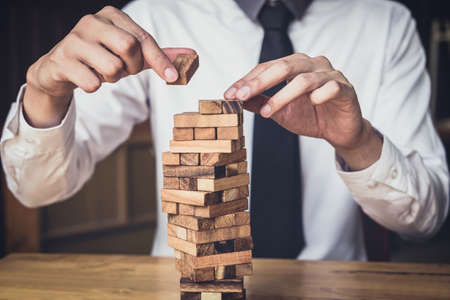 Images of hand of businesspeople placing and pulling wood block on the tower, Alternative risk concept, plan and strategy in business, Risk To Make Business Growth Concept With Wooden Blocks.の写真素材