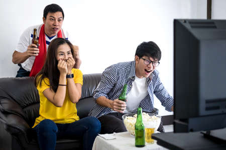 Group of friends fanclub watching soccer match on tv and cheering football team, celebrating with beer and popcorn at home, sports and entertainment concept.の写真素材