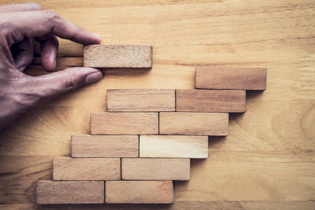 Business concept for growth success process, Images of hand of businesspeople placing and pulling wood block to complete in game and success in strategy.の写真素材