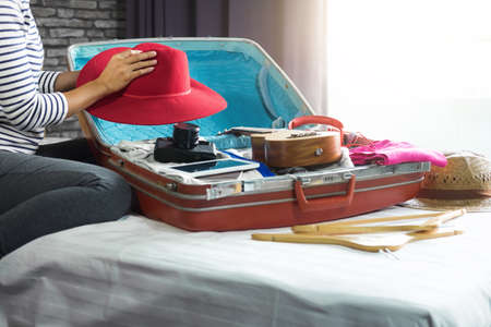 Travel and vacation concept, happiness woman packing stuff and a lot of clothes into suitcase on bed prepare for her travel and journey trip.の写真素材