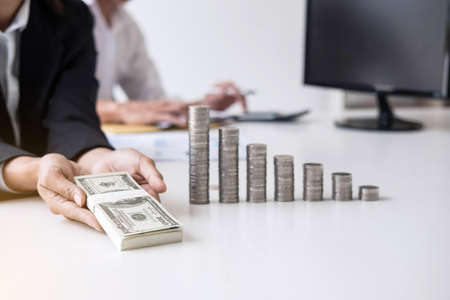 Business accountant or banker, Two business partner analysis with stock financial indices and growth stacking coin and financial costs wisely and carefully, investment and saving concept.の写真素材