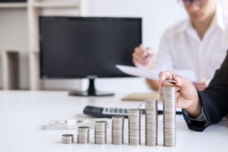 Business accountant or banker, Two business partner analysis with stock financial indices and growth stacking coin and financial costs wisely and carefully, investment and saving concept.の写真素材