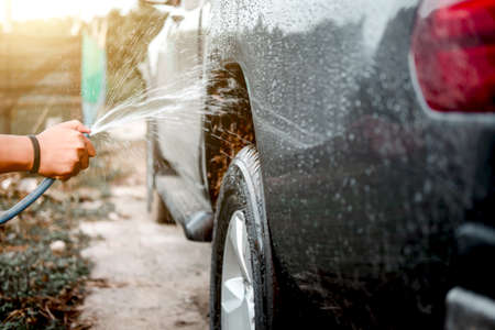 Man washing and cleaning car with spraying pressured water.の写真素材