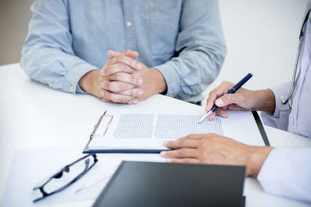 Doctor filling up an history form while consulting to patient and recommend treatment methods and how to rehabilitate.の写真素材