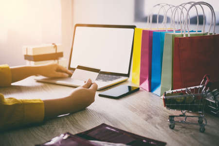 Young woman typing laptop for online shopping website and holding card pay by credit card, Online payment and shopping concept.の写真素材