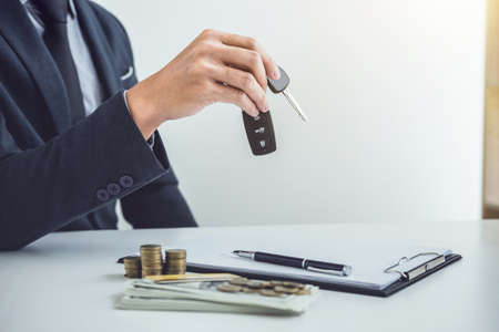 Salesman send key to customer after good deal agreement, successful car loan contract buying or selling new vehicle.の写真素材