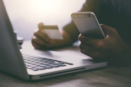 Man typing laptop and using smartphone for online shopping and pay by credit cardの写真素材