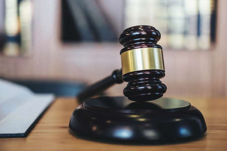 Scales of justice and gavel on sounding block and law book to working with judge agreement in...
