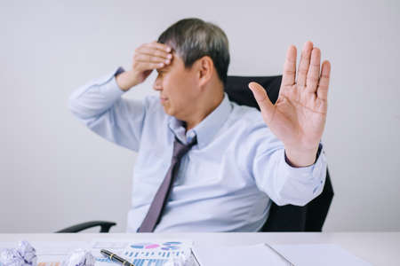Feeling sick and tired, Senior businessman depressed and exhausted, businessman at his desk frustrated with problems with a pile of work and keeping eyes closed while sitting on office.の写真素材