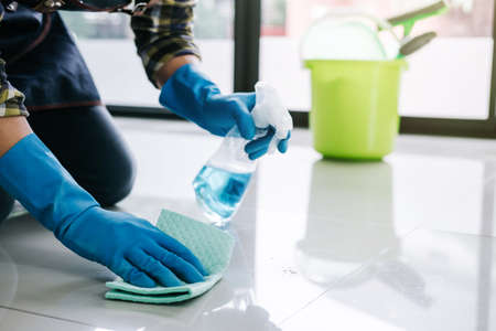 Husband housekeeping and cleaning concept, Happy young man in blue rubber gloves wiping dust using a...