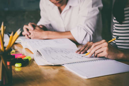 High school or college student group catching up workbook and learning tutoring in classroom and reading, doing homework and lesson practice preparing exam.の写真素材