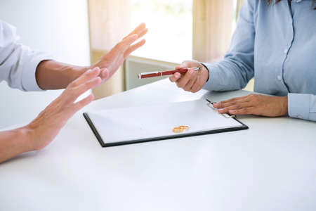 Husband and wife are reading divorce agreement and filing pen to signing decree of divorce (dissolution or cancellation) of marriage filing divorce papers and two golden marry ring.の写真素材