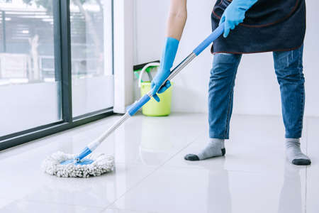 Housekeeping and cleaning concept, Happy young woman in blue rubber gloves wiping dust using mop...