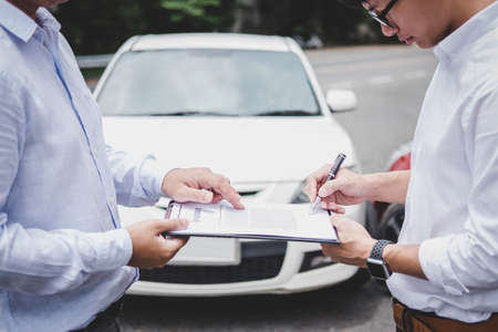 Insurance Agent examine Damaged Car and customer filing signature on Report Claim Form process after accident, Traffic Accident and insurance concept.の写真素材