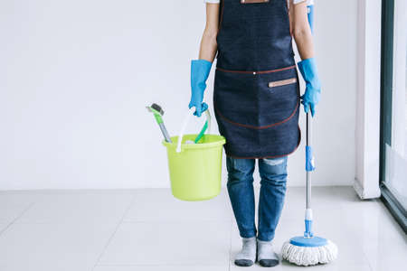 Housekeeping and cleaning concept, Happy young woman in blue rubber gloves holding mop and plastic...
