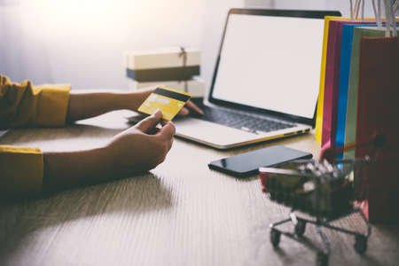Young woman typing laptop for online shopping website and holding card pay by credit card, Online payment and shopping concept.の写真素材