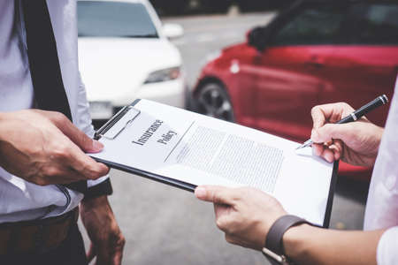 Insurance Agent examine Damaged Car and customer filing signature on Report Claim Form process after...