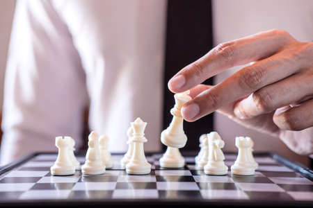 Hand of confident businessman use king chess piece white playing chess game to development analysis...