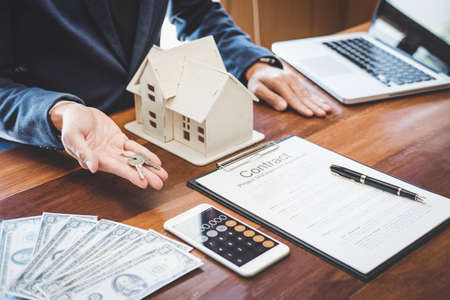 Real estate agent Sales manager holding filing keys to customer after signing rental lease contract...