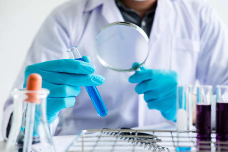 Biochemistry laboratory research, Scientist or medical in lab coat holding test tube with reagent...