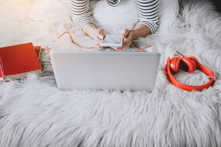 Young happiness woman on bedroom in enjoying listen the music with smart phone in holiday, relaxation and recreation concept.の写真素材